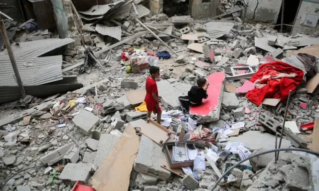 Palestinian children inspect the site of an Israeli strike on a house in Rafah, in the southern Gaz
